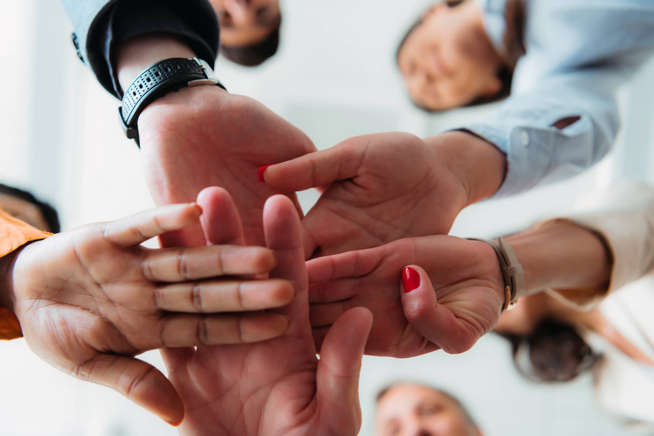 View of diverse multiethnic businesspeople give fists bump engaged in teambuilding activity at meeting, multiracial colleagues join hands show unity and support at briefing in office